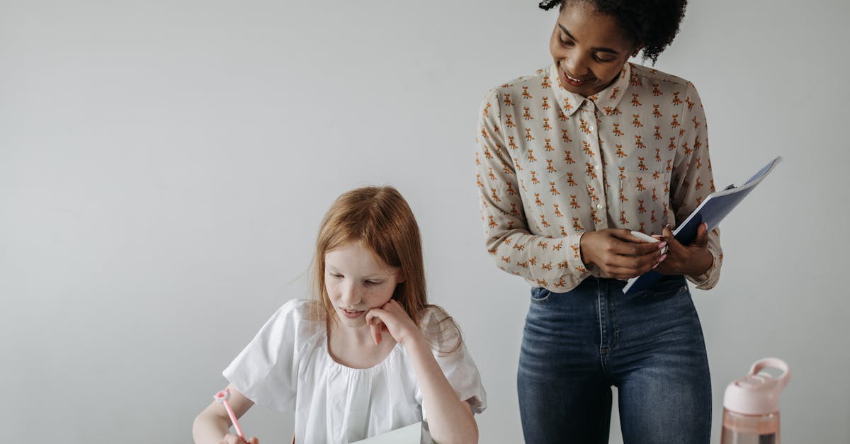 Teacher guiding an elementary student through a writing assignment at a classroom desk, providing one-on-one focus support.
